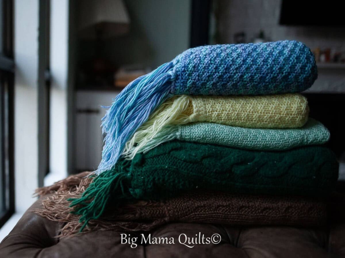 Stack of knitted heirloom afghans on a footstool.