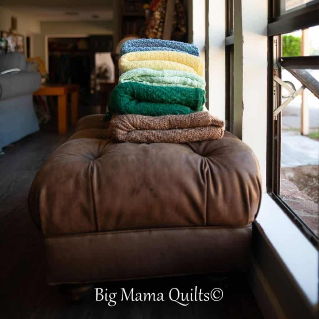 Stack of heirloom knitted blankets on a footstool.
