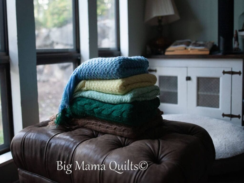 Stack of heirloom knitted blankets on a footstool.