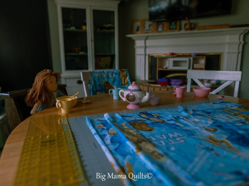 Little girls' tea party with a doll at a sewing table with Star Wars fabric ready to cut.  Learn to quilt.